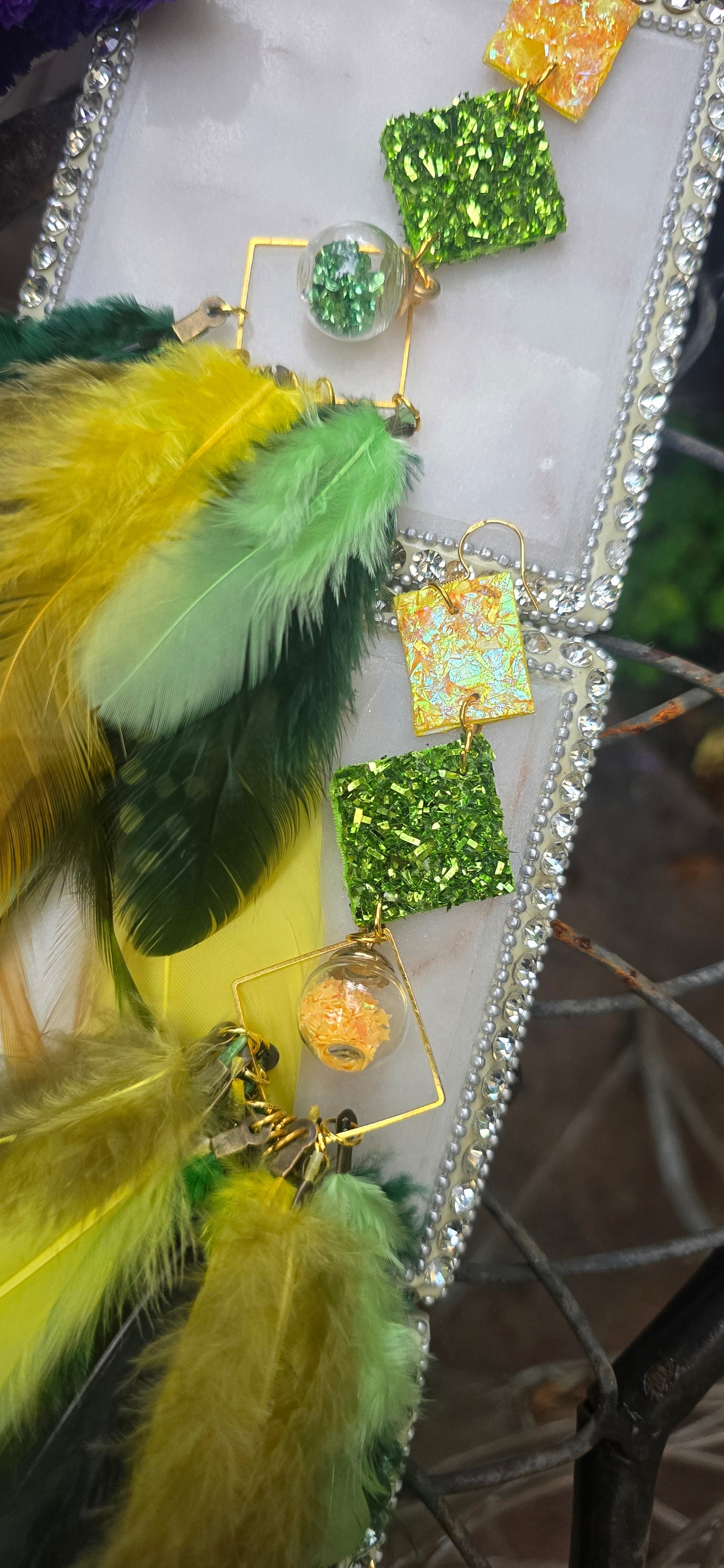 Green boho festival feather earrings by Claire, showcasing vibrant feathers and intricate design perfect for stylish outfits.