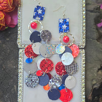 Red and blue sparkly round dangle earrings from Shop Moxxc, featuring a shiny, festive design with sparkling embellishments.