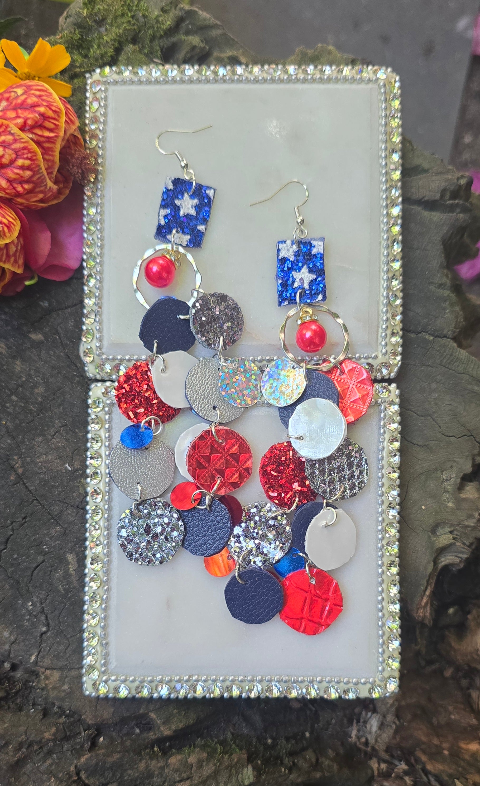 Red and blue sparkly round dangle earrings from Shop Moxxc, featuring a shiny, festive design with sparkling embellishments.