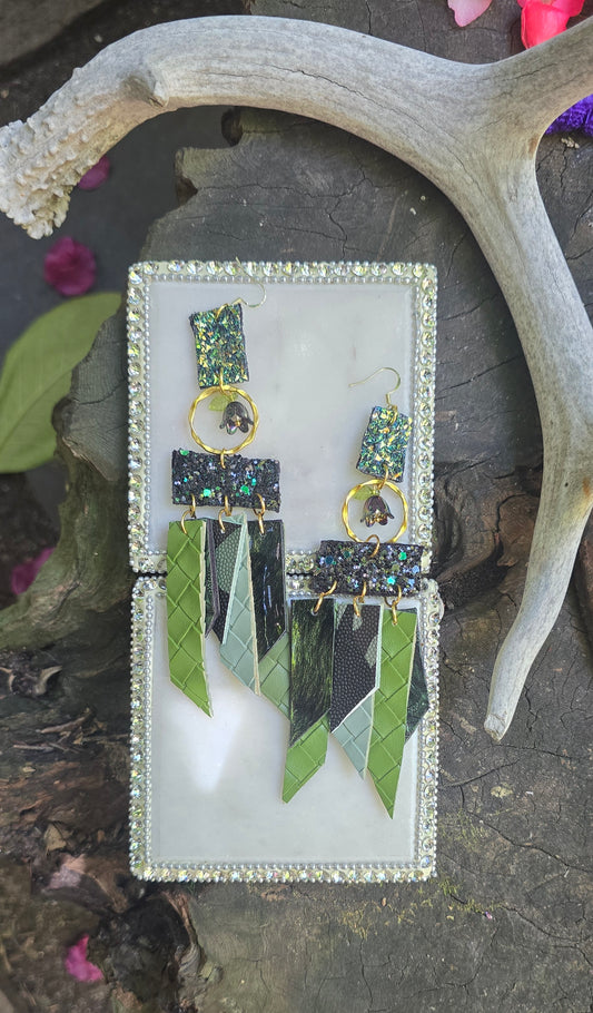 Green glittery fringe earrings called Ruth from Shop Moxxc hanging with shimmering details and fringe design on a white background.