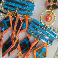 Orange geometric fringe earrings by Shop Moxxc featuring bold, modern design with intricate fringe details and vibrant color.