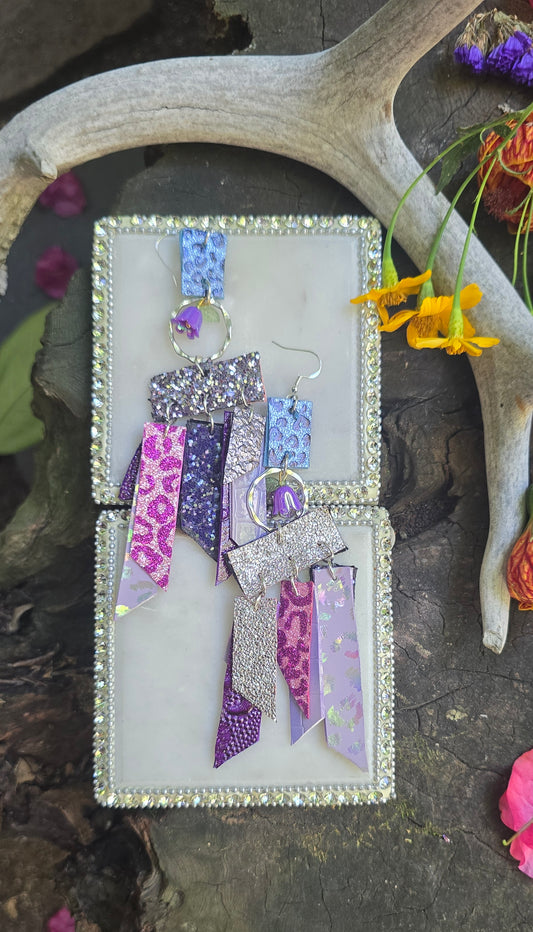 Purple glittery fringe earrings by Shop Moxxc featuring long, shimmering tassels and metallic accents.