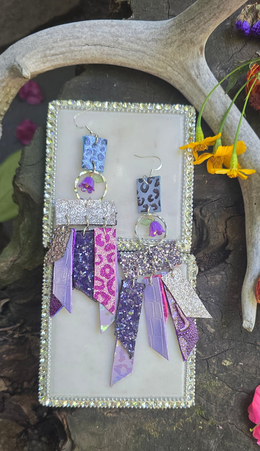 Purple glittery fringe earrings by Shop Moxxc featuring long, shimmering tassels and metallic accents.