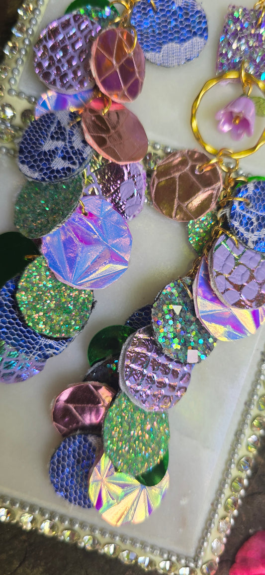 Purple iridescent round dangle earrings by Shop Moxxc featuring sleek, shiny surfaces and elegant hook attachments.